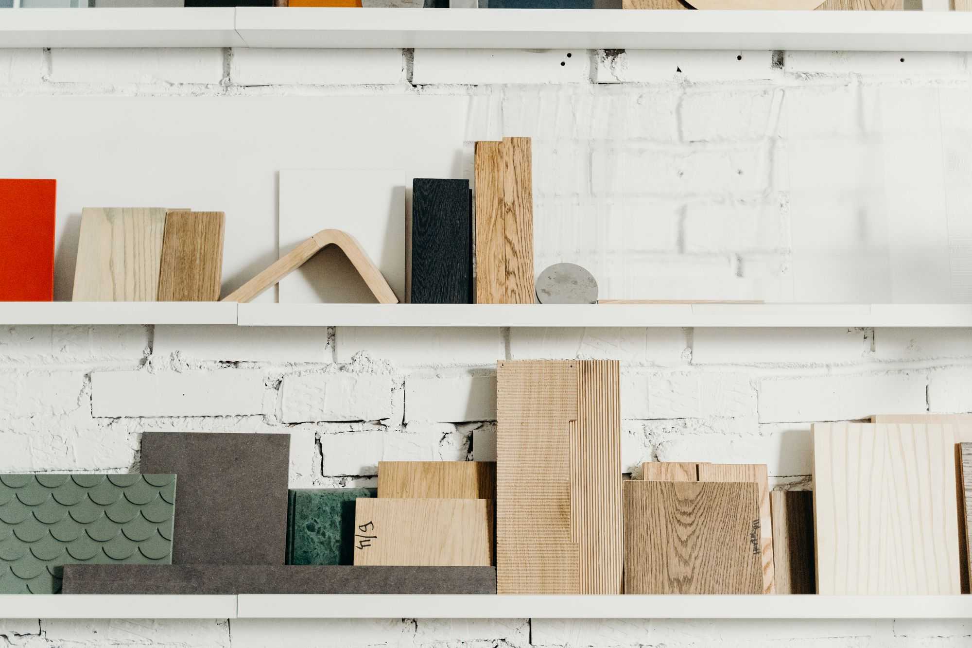 Weiße Regale mit Mustern aus Holz, Stein und farbigen Platten