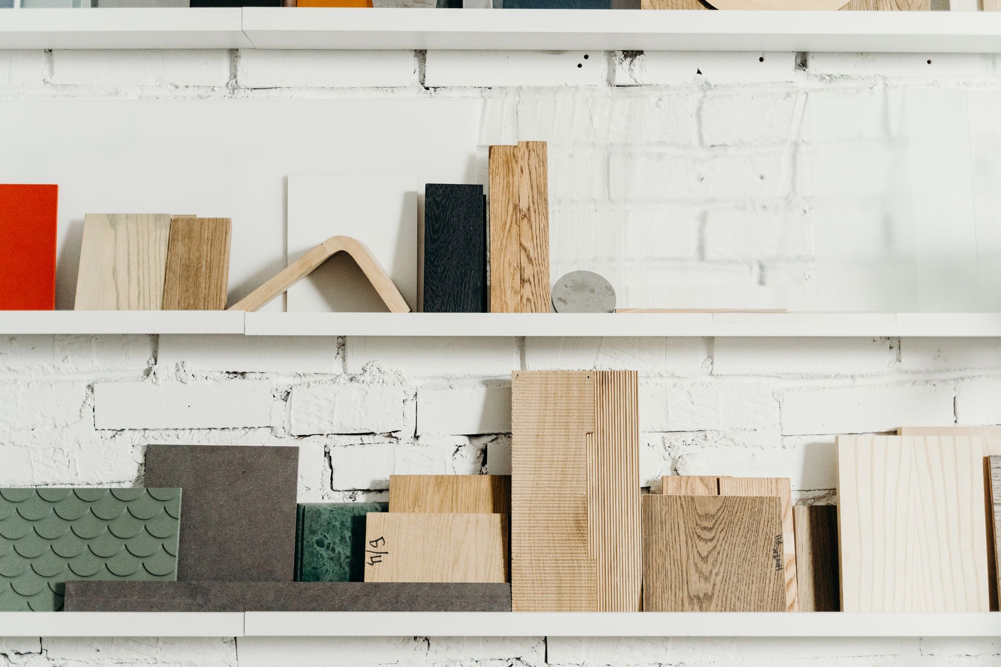 Weiße Regale mit Mustern aus Holz, Stein und farbigen Platten