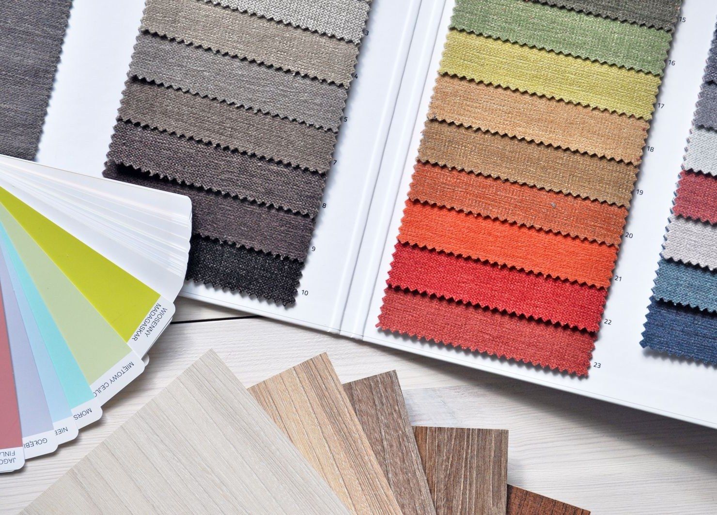 Stoffmuster in vielen Farben, ein Farbfächer und Muster von Bodenbelägen auf einem Tisch